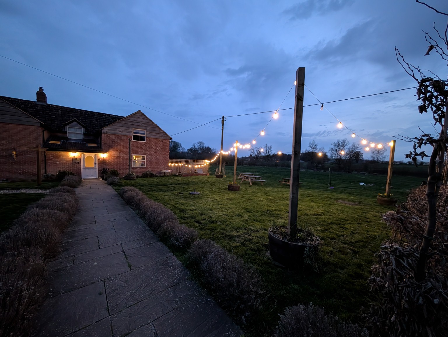 The path to Elderbrook House at dusk, festoon lights strung across the garden.