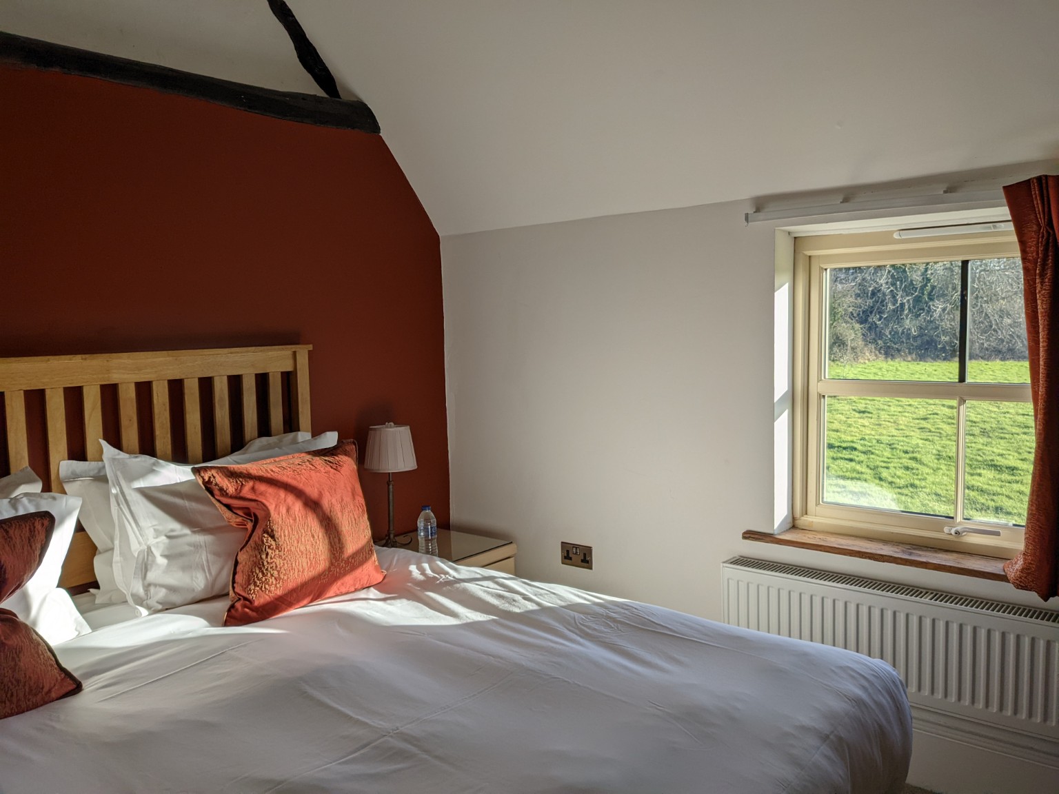 Pratchett: the king bed beside the window, with red curtains and a view over the field.